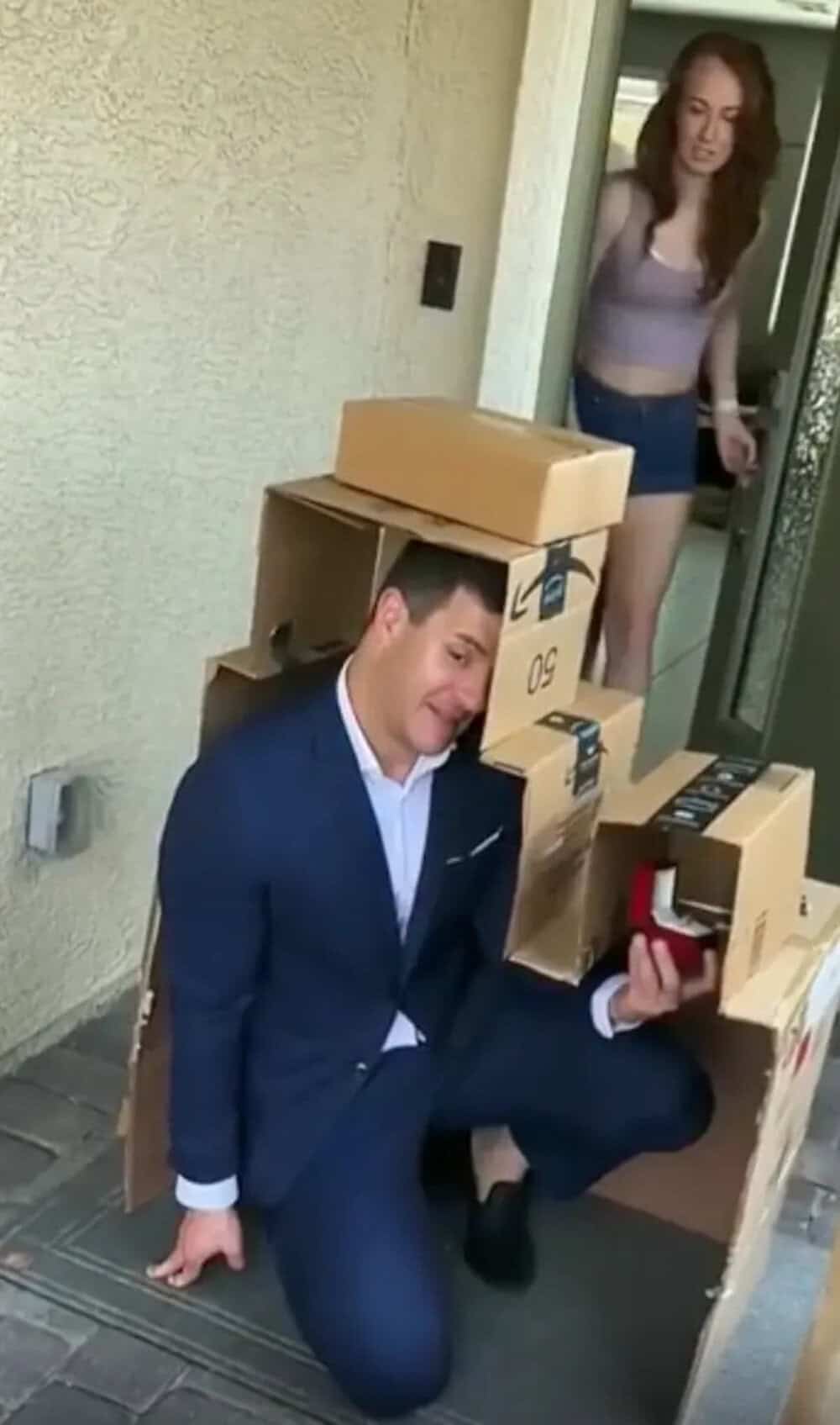 Man in suit with cardboard boxes on his back, woman watching, funny scene.