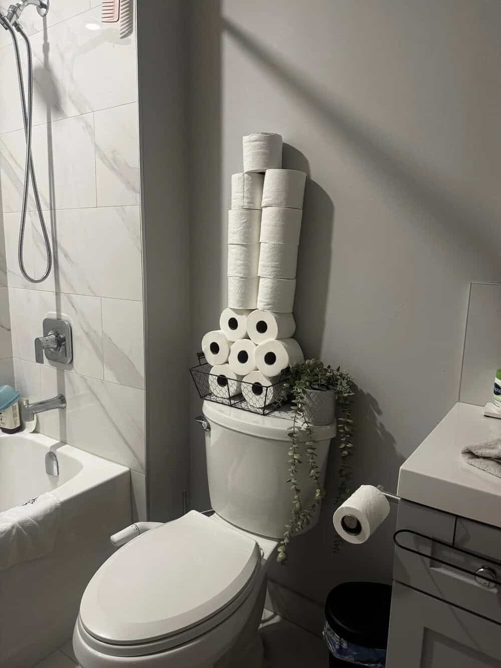 Stacked toilet paper rolls on top of a toilet tank in a bathroom.