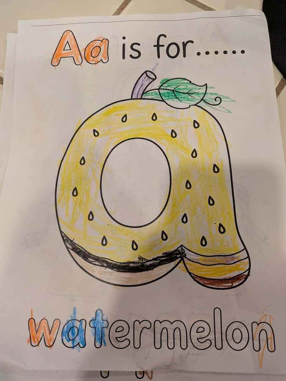 Letter A and a yellow watermelon drawing with green leaves and a purple stem.