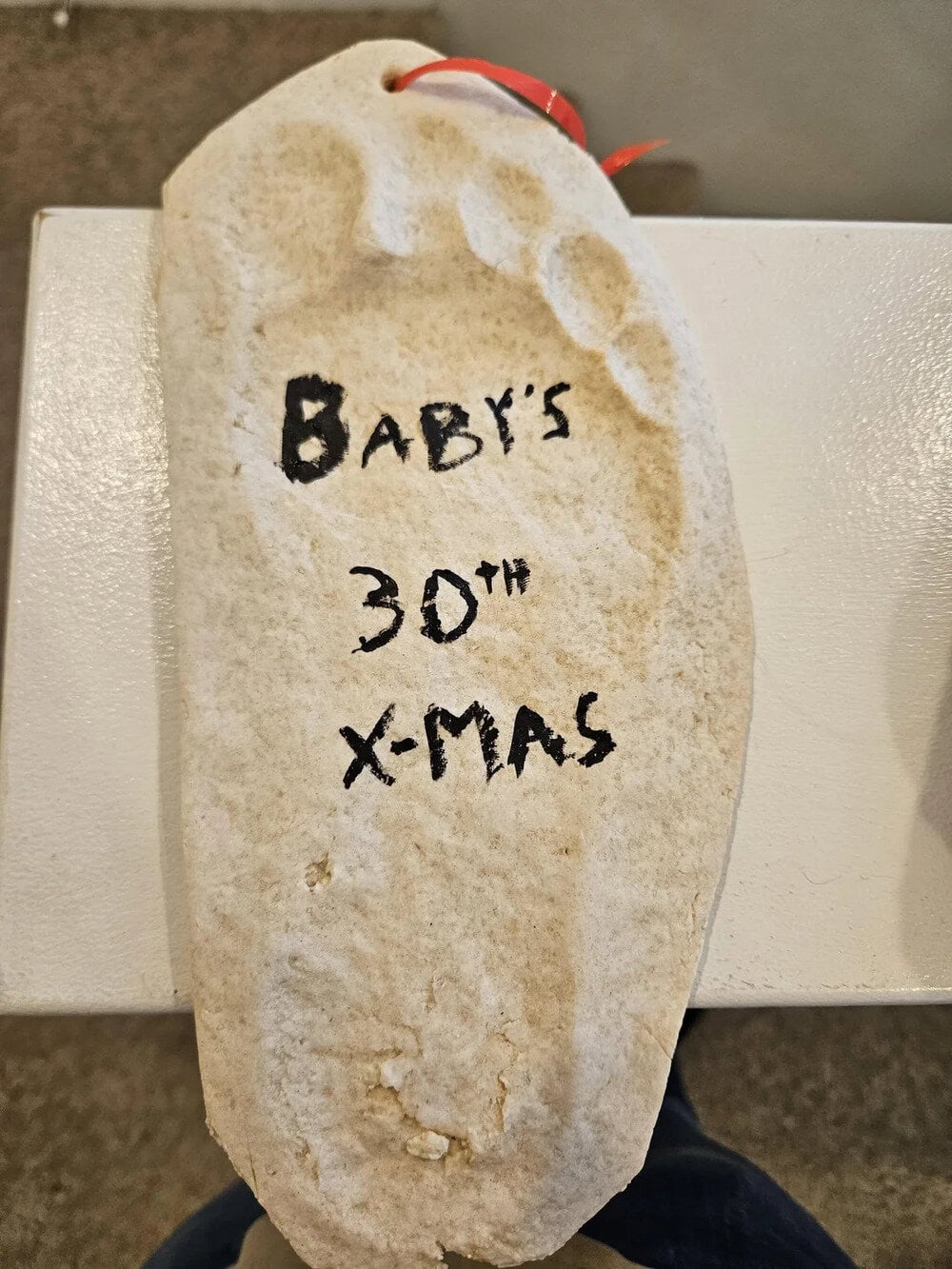 Footprint with text 'BABY'S 30TH X-MAS' written on it.