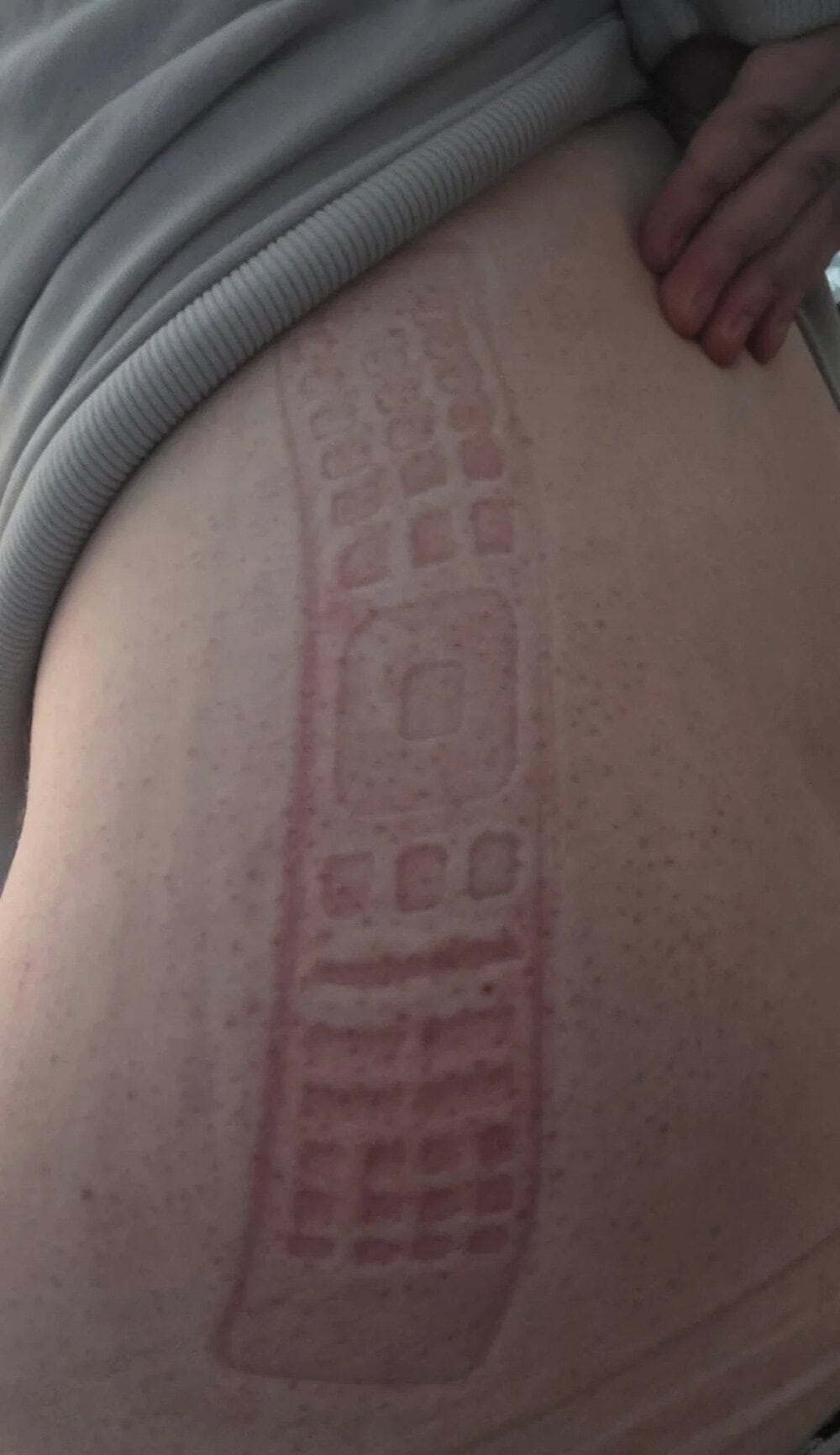 A tattoo of a keyboard on a person's side, with a hand resting on the skin.