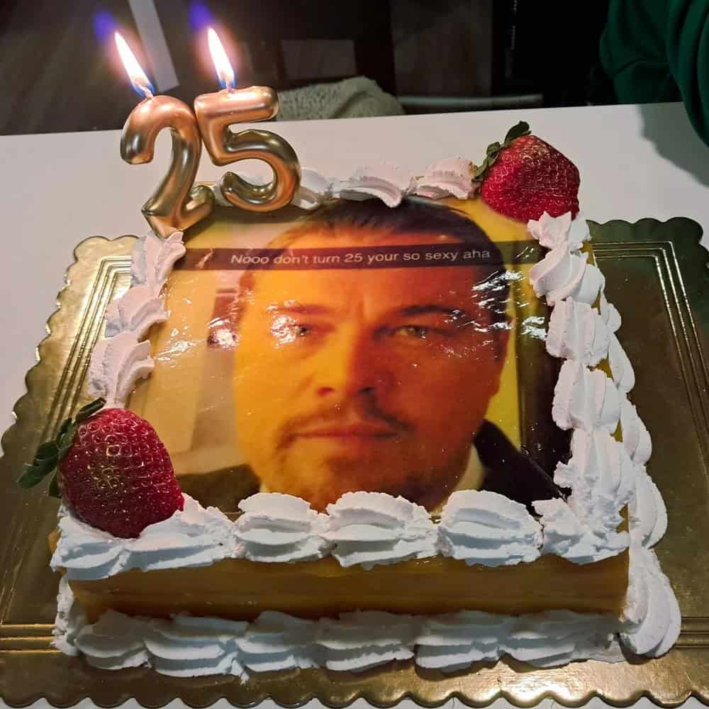 Cake with a photo of a man's face, strawberries, and candles shaped as '25'.