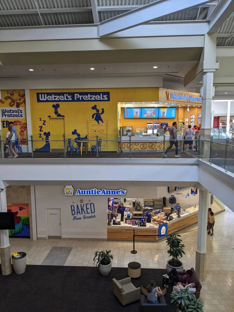 Wetzels Pretzels stand in a shopping mall with customers and a yellow wall with reindeer.