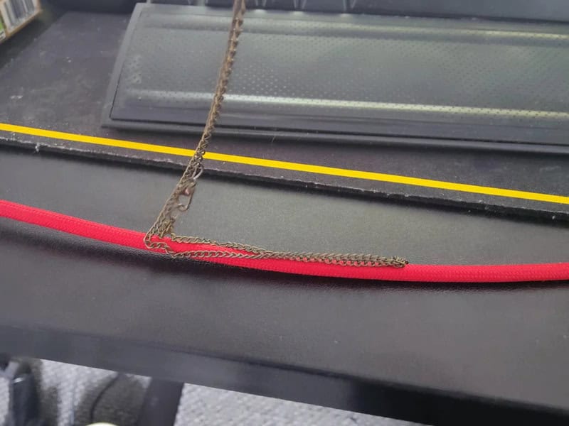 A red leash and a yellow leash are tangled on a black surface.
