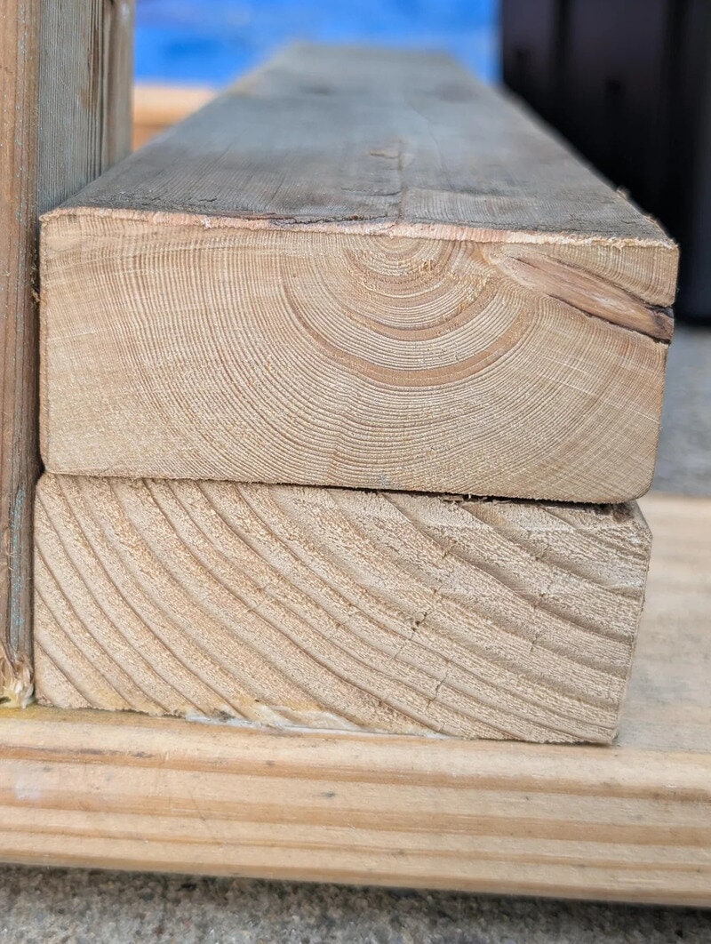 Close-up of two stacked wooden beams with visible grain and cut edges.