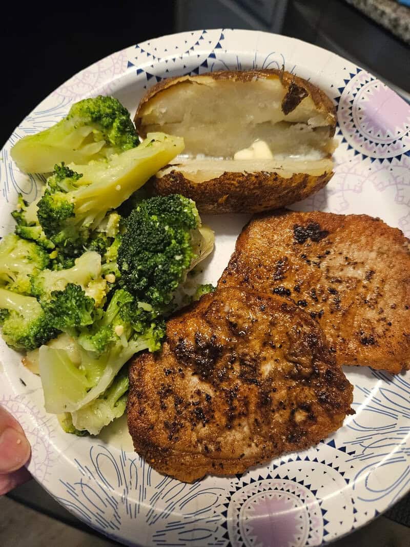 Fried fish fillets, broccoli, and a baked potato on a paper plate.