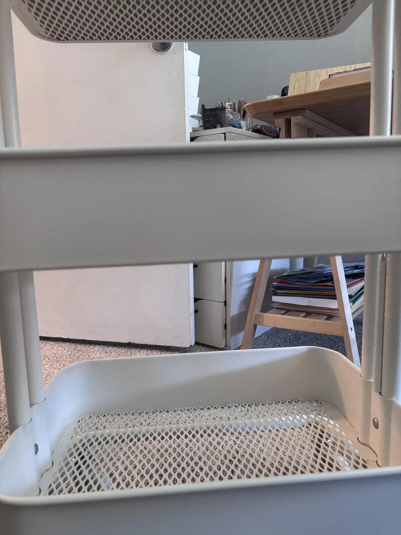 View of a white plastic chair with a mesh bottom, taken from below.