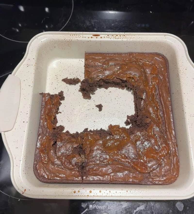 A square chocolate cake with a missing center, on a white baking dish.
