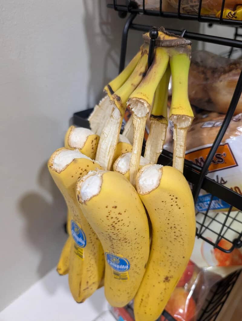 Bunch of bananas with white mold on the stems hanging in a store.
