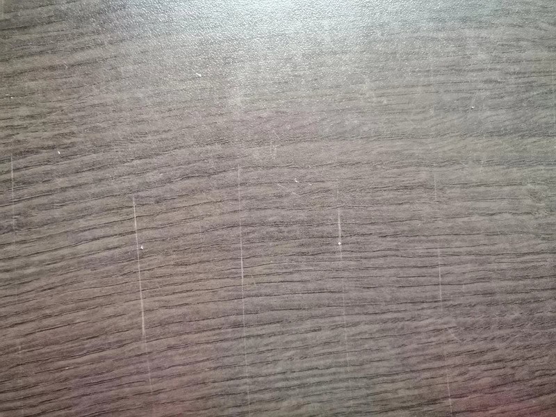 Scratched wooden surface with visible marks and lines.