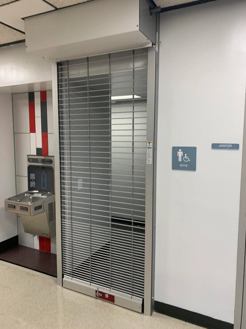 Closed bathroom with metal security shutter in a public building.