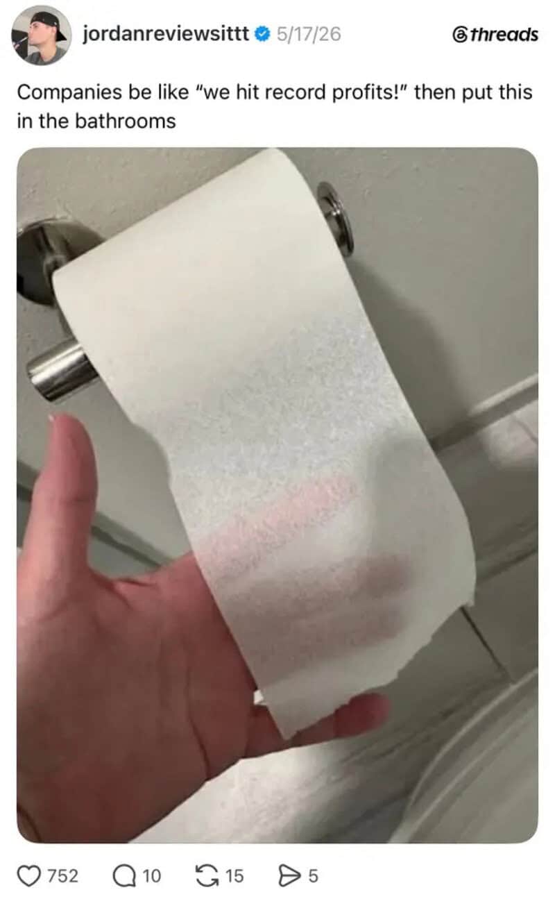 Toilet paper roll with a pink streak, held in a person's hand in a bathroom.