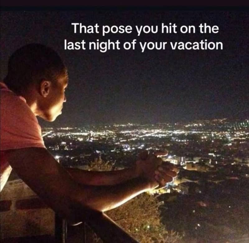 Person looking at city lights at night with caption about vacation pose.