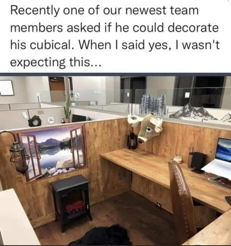 Cubical decorated with a reindeer mask, mountain picture, and small fireplace.