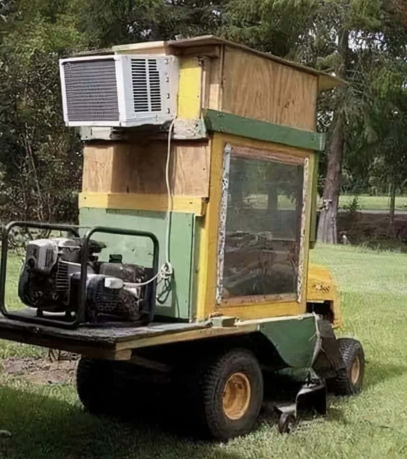 Homemade small vehicle with a window, air conditioner, and generator on a grassy field.