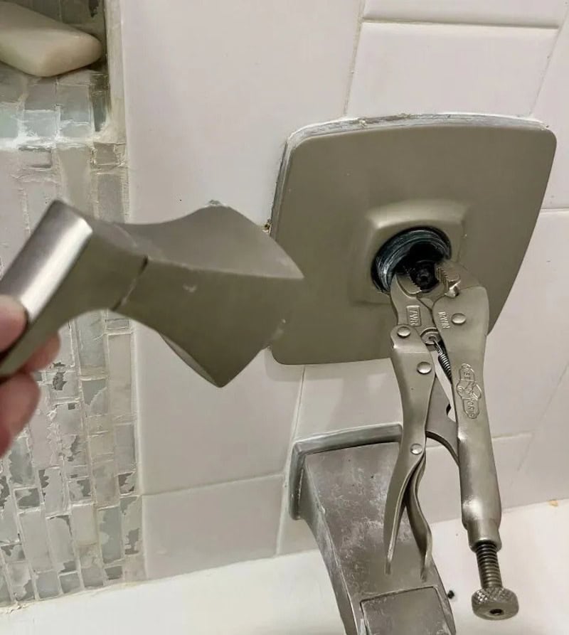 Hammer and pliers used to remove a light switch cover in a bathroom.