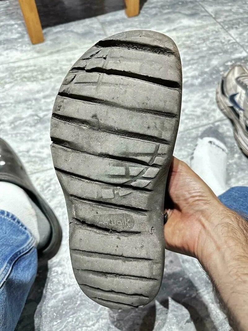 Worn out shoe sole with uneven tread pattern and visible wear.