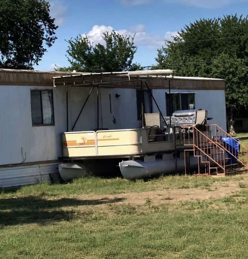 A house with a pontoon boat attached to the front, serving as a porch.