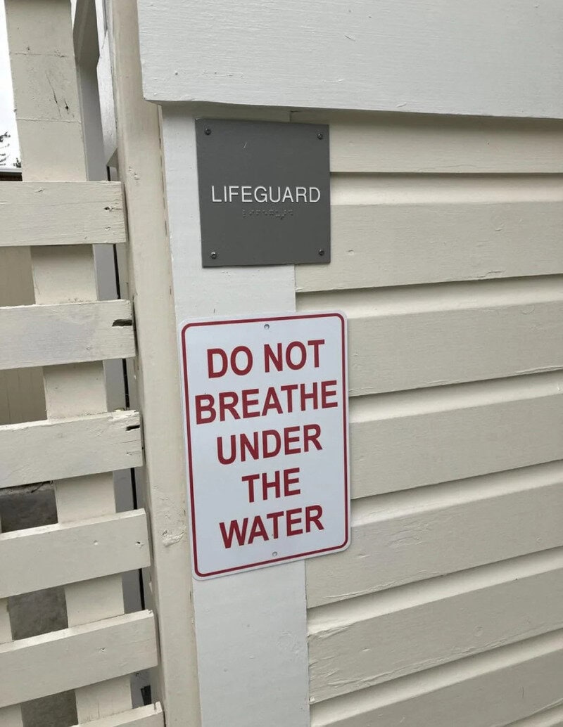 Sign on wall says 'DO NOT BREATHE UNDER THE WATER' with a lifeguard sign above.