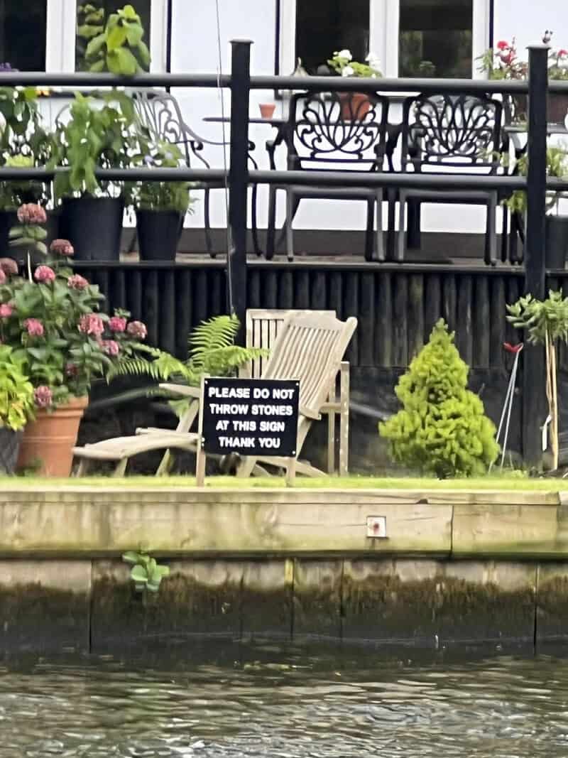 Sign on a chair says 'Please do not throw stones at this sign thank you'.