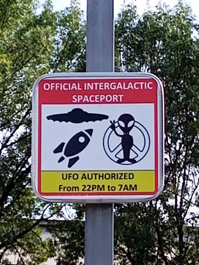 Official intergalactic spaceport sign with UFO and alien, authorized from 10PM to 7AM.