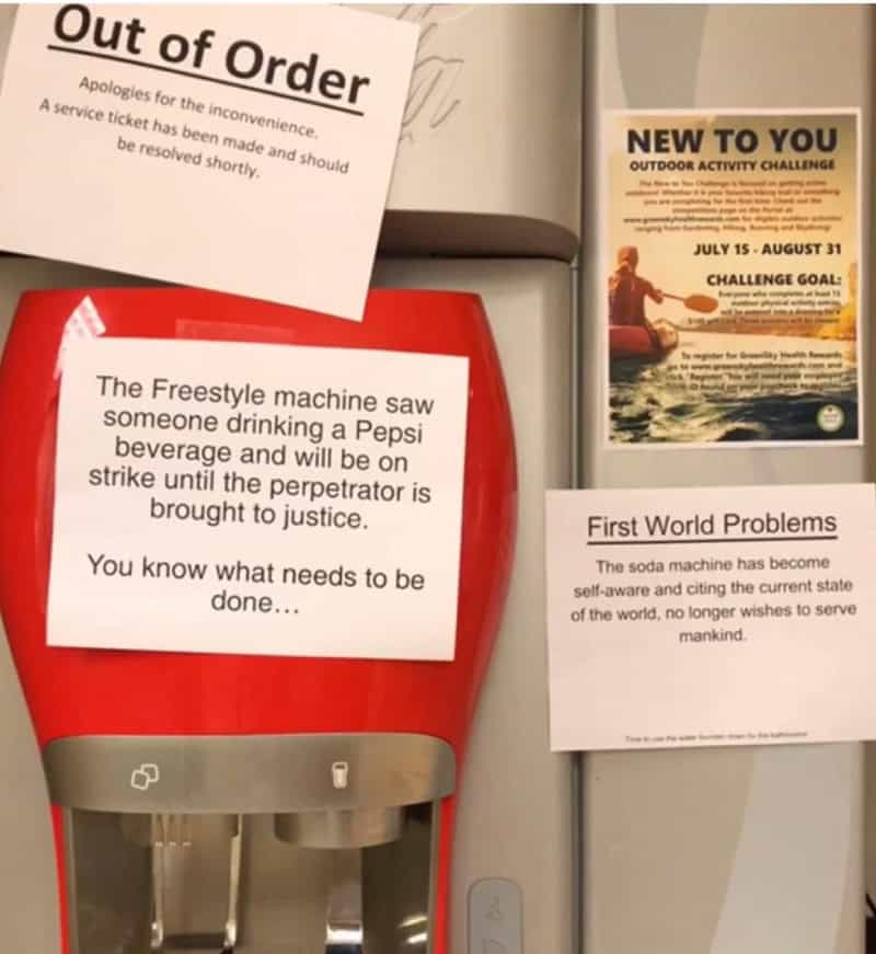 Signs on a wall including 'Out of Order', 'The Freestyle machine saw someone drinking a Pepsi', 'New.