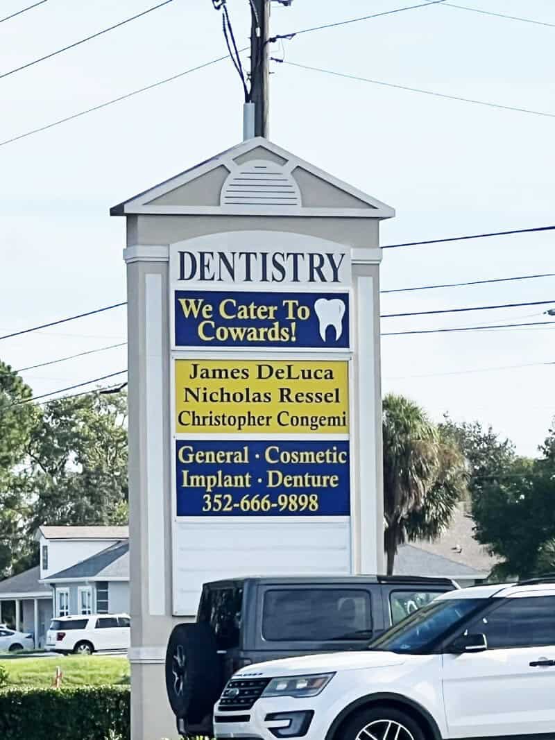 Dentistry sign with humorous message for cowards and list of dentists.