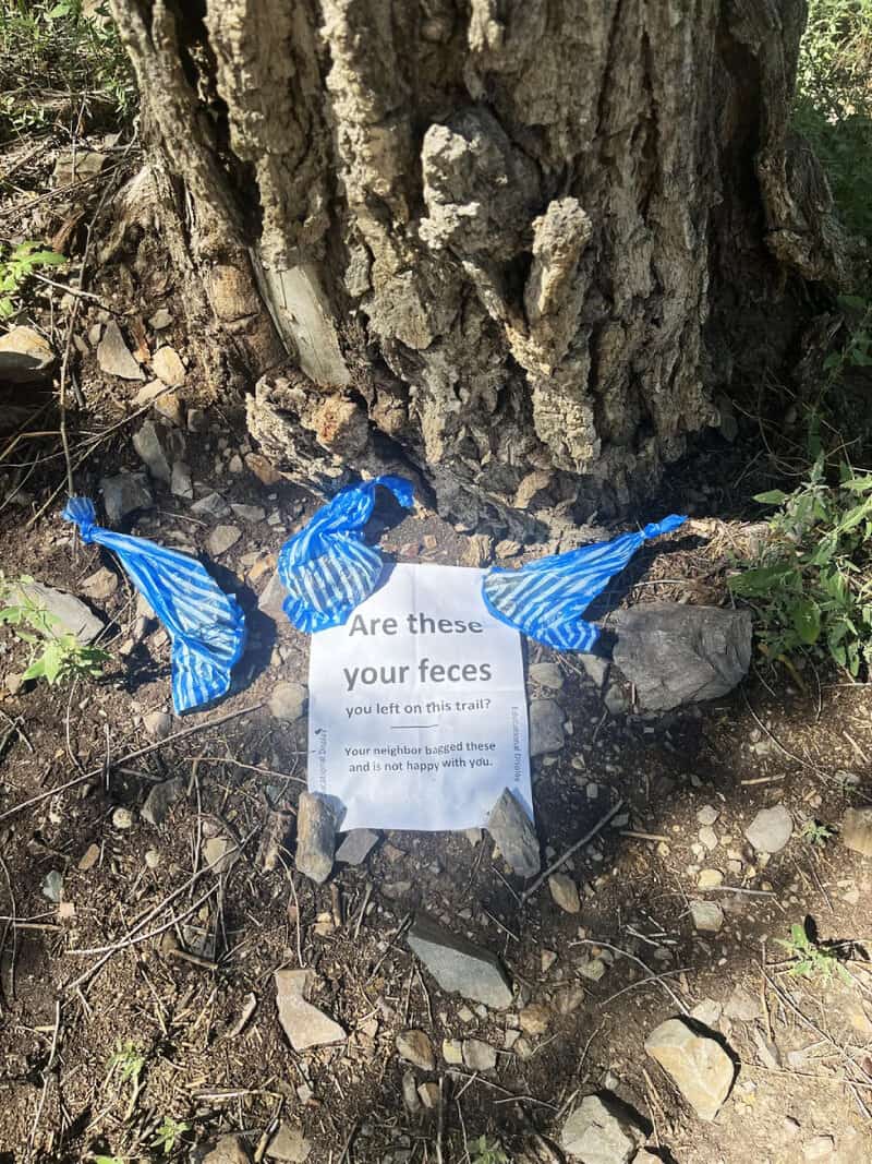 Sign on trail asks, 'Are these your feces? You left on this trail!'.