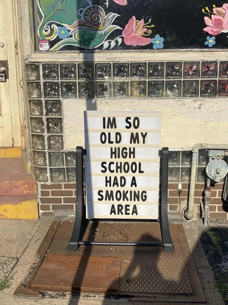 Sign reads 'I'm so old my high school had a smoking area' outside a building.
