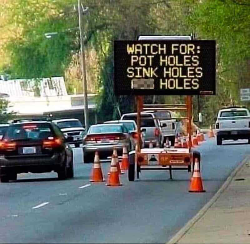 Sign warns to watch for pot holes, sink holes, and holes in the road.