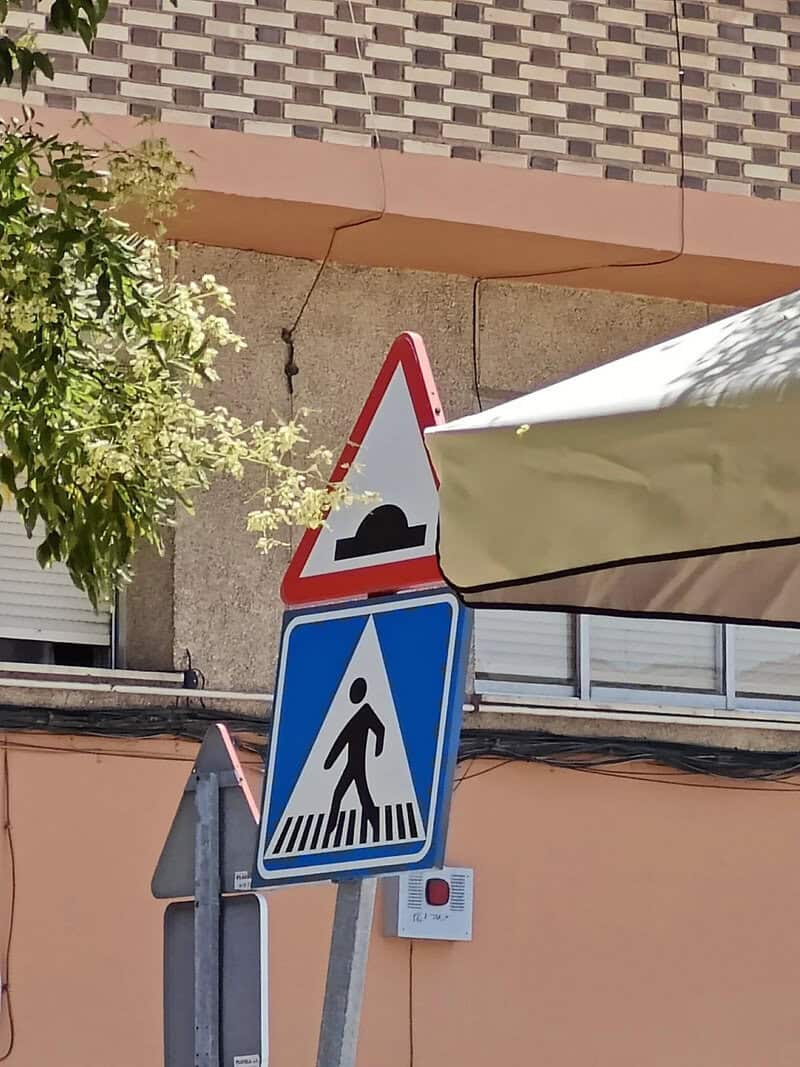 Humorous road sign with a speed bump and pedestrian crossing.