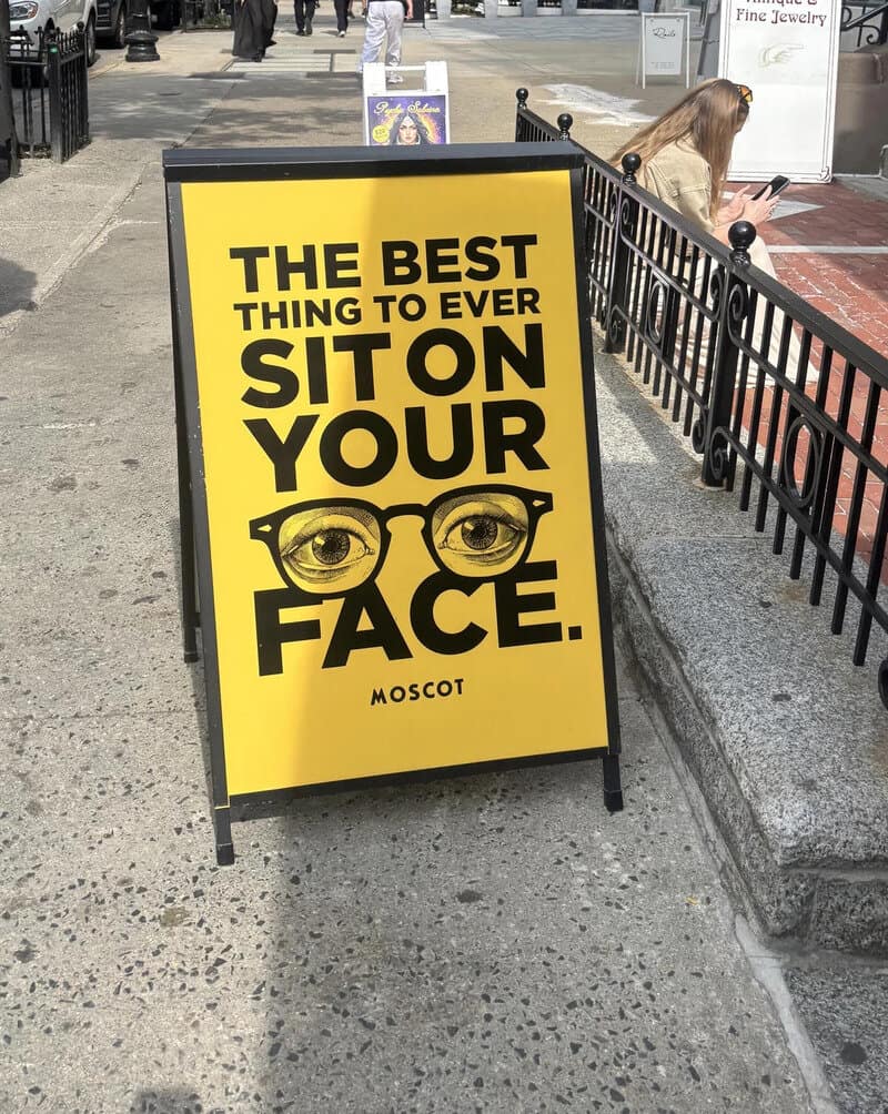 Sign reading 'The best thing to ever sit on your face' with glasses illustration.