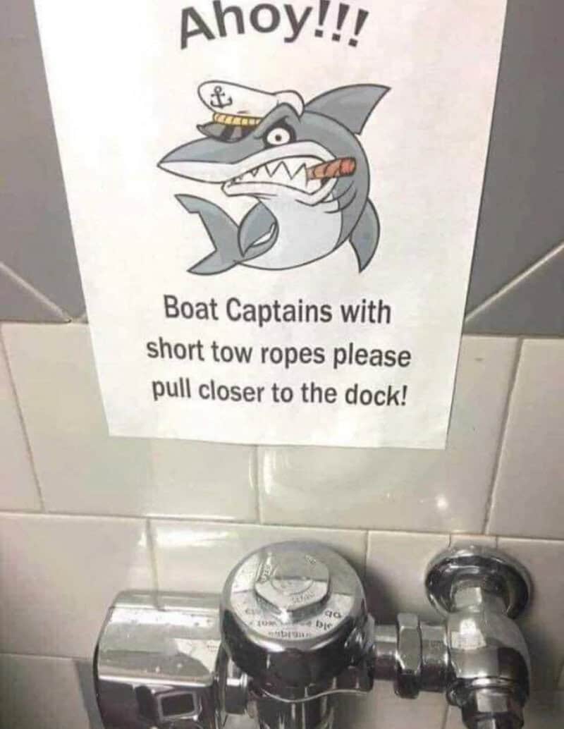 Sign with a cartoon shark and boat captain, warning about short tow ropes.