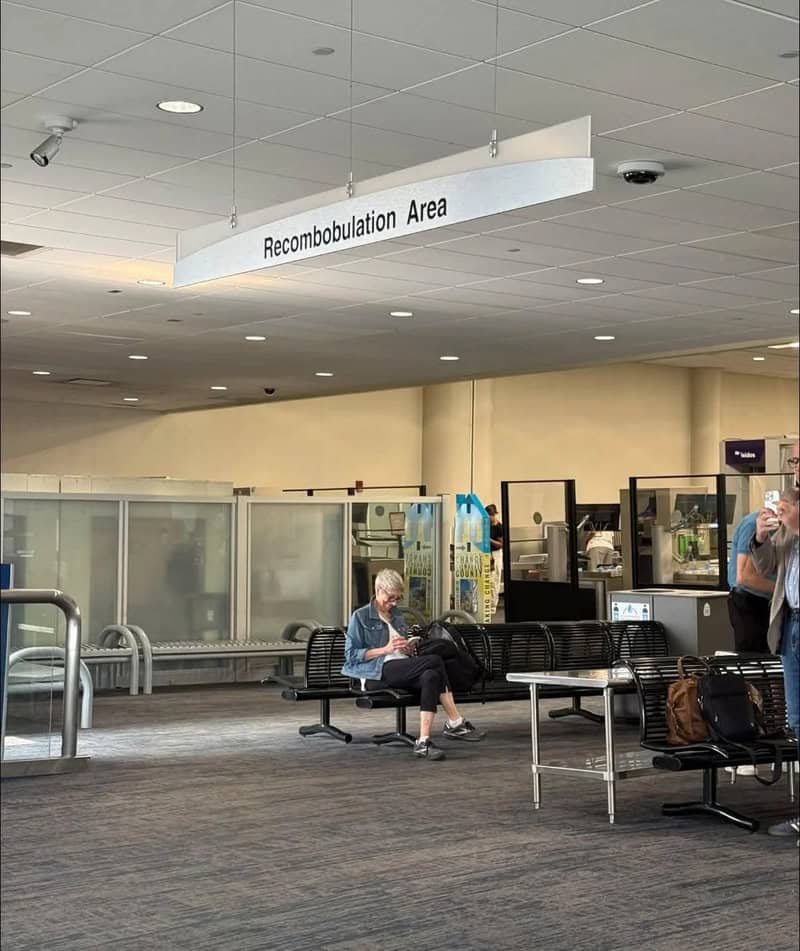 Recombobulation Area sign at airport with seating and travelers.