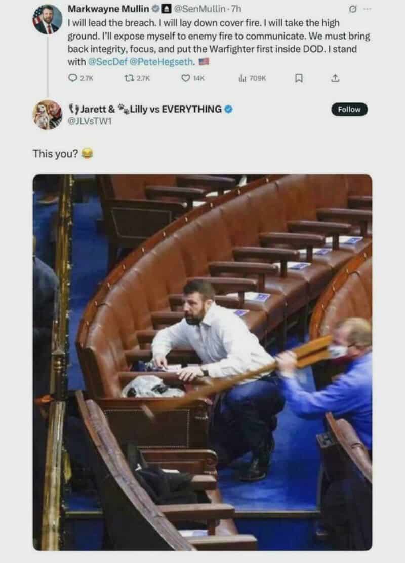 Man sitting alone in a large, empty legislative chamber with wooden desks.