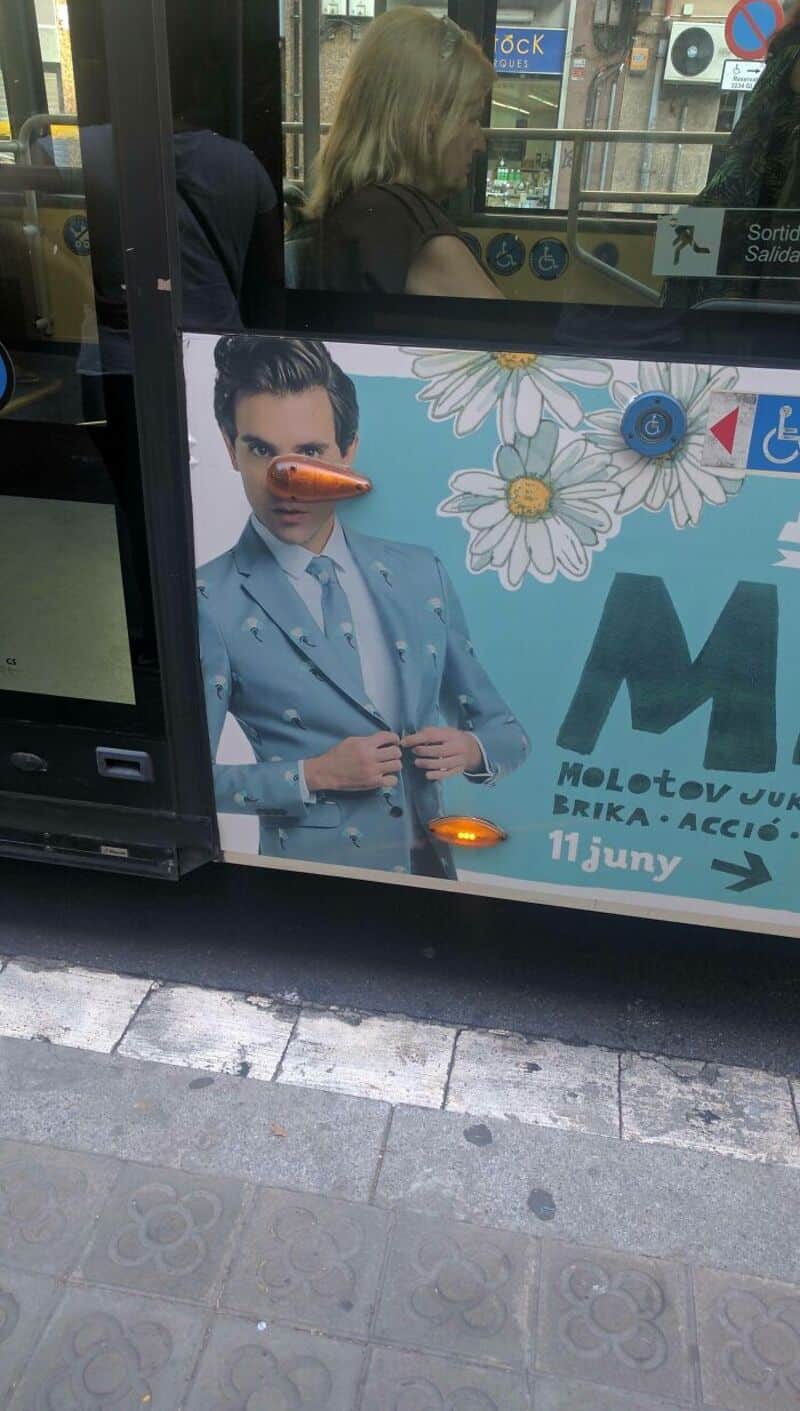 Bus with a poster of a woman in a blue suit and daisies, and a nose-shaped object on the poster.