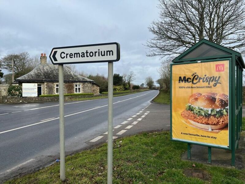 Road sign pointing to Crematorium and McDonald's advertisement for McCrispy.