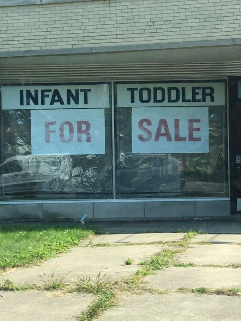 Infant for sale and toddler for sale signs in store window.