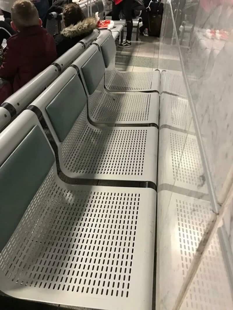 Empty airport seats with a person in a red jacket sitting nearby.
