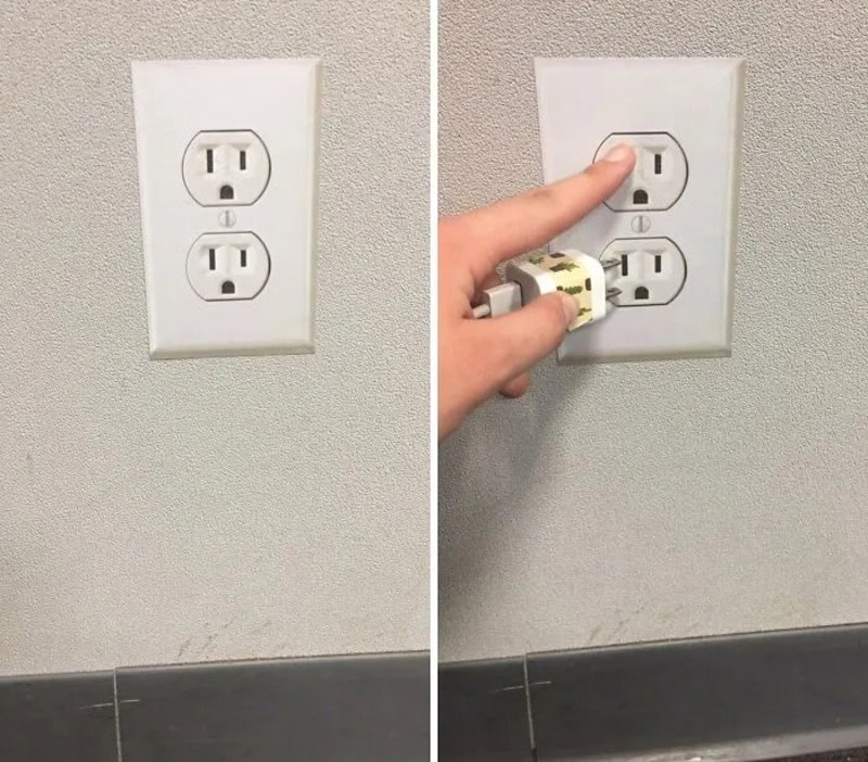 Power outlet with a finger pointing at the top socket, showing a plug with a cartoon character.