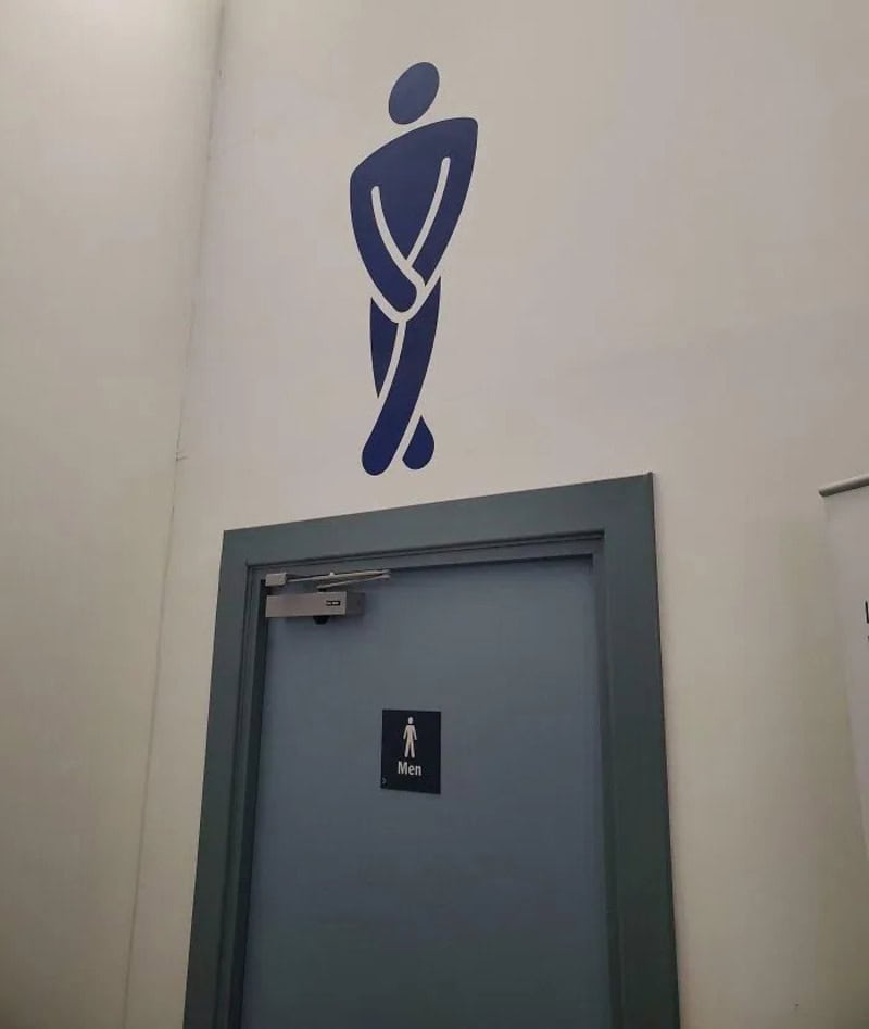 Men's restroom door with a large, humorous sign of a man crossing his legs.