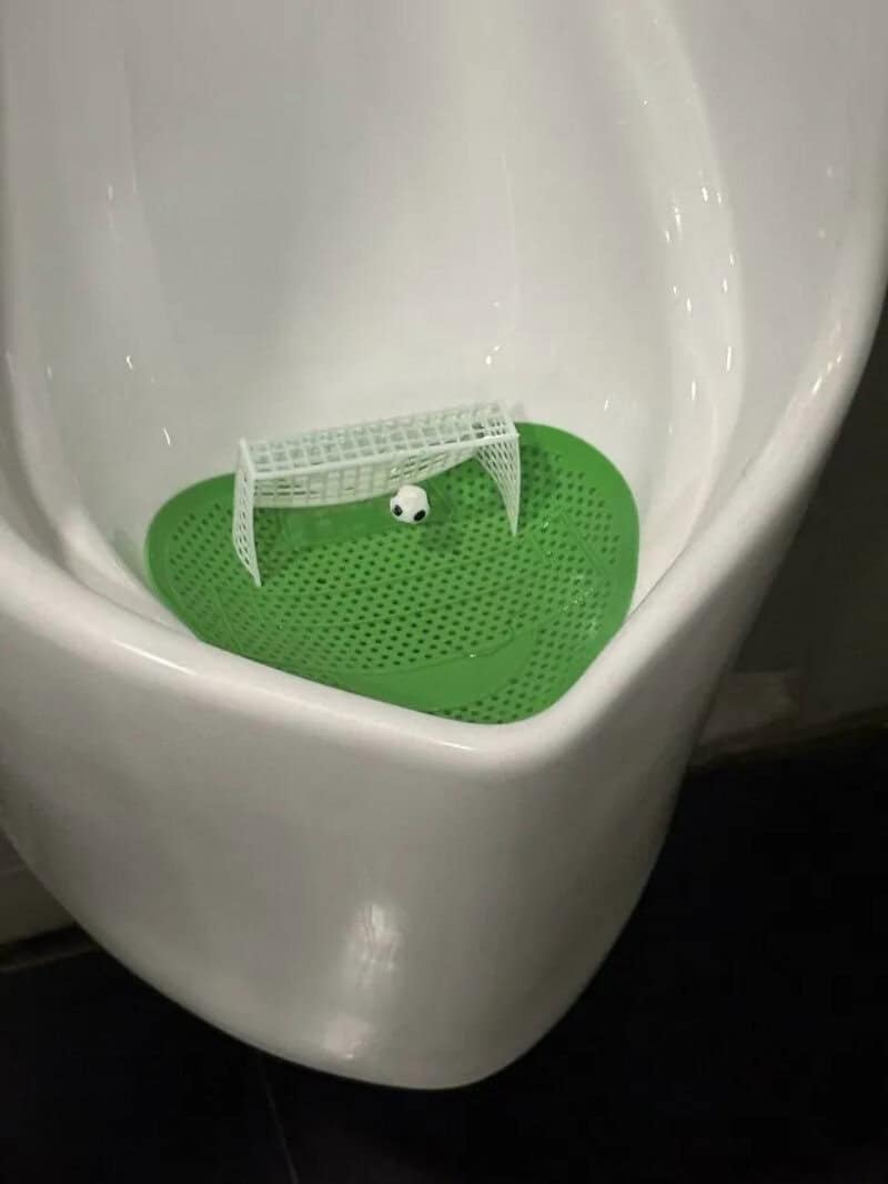 Mini soccer goal inside a urinal with a small ball.