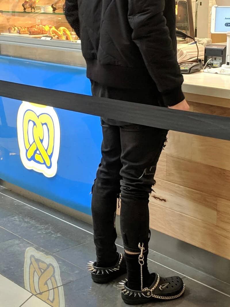 Person in black clothing and spiked boots at a food counter.