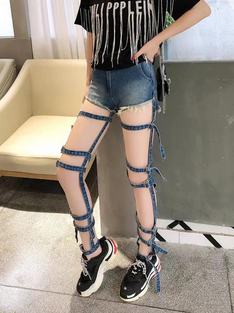 Person wearing ripped shorts and unique leg straps with sneakers.
