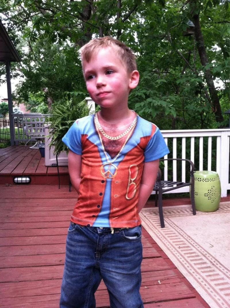 Young boy in a colorful shirt with a peace sign necklace on a deck.
