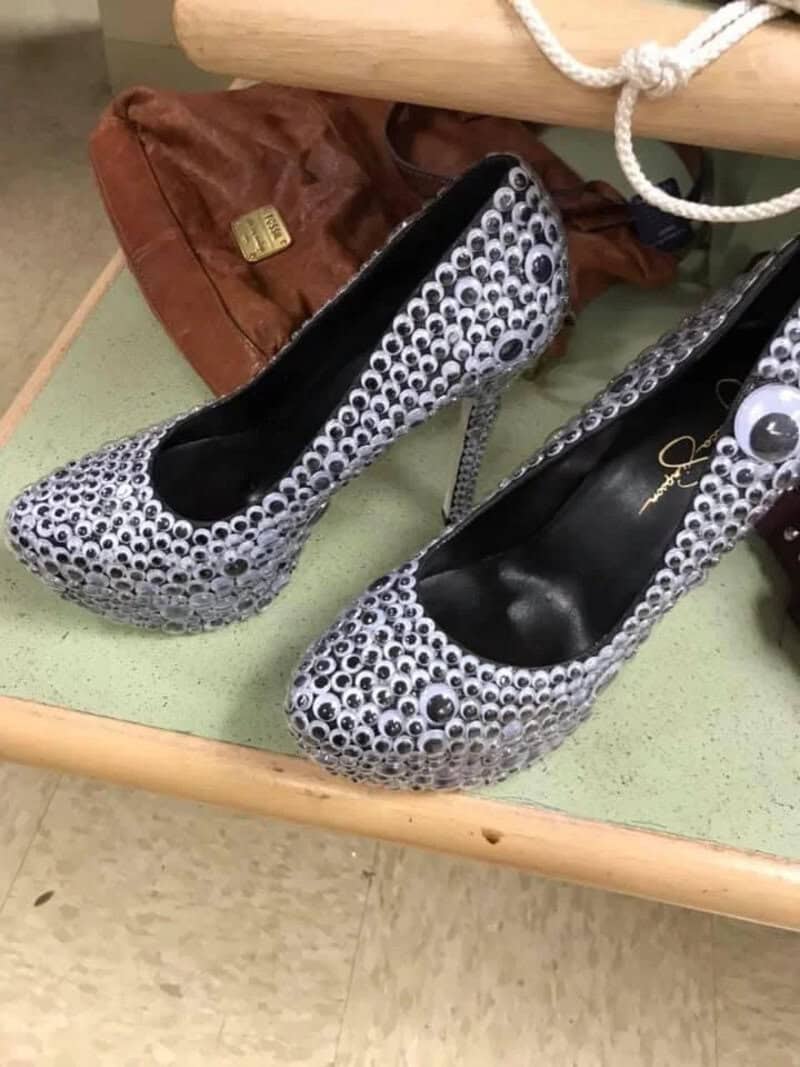 High-heeled shoes covered in numerous small eye-like decorations.