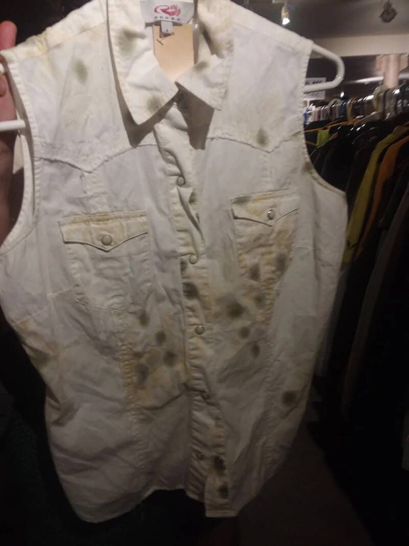 Sleeveless white denim vest with front pockets and button closure.