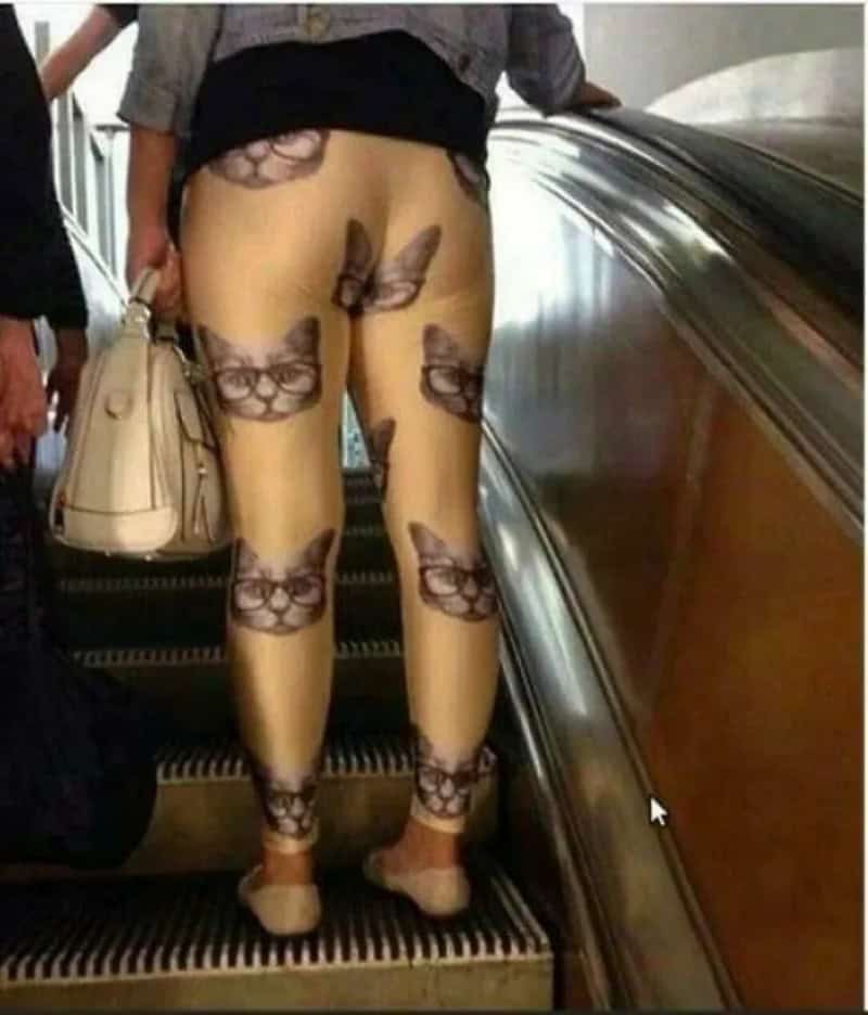 Leggings with a print of multiple cat faces, worn by a person on an escalator.