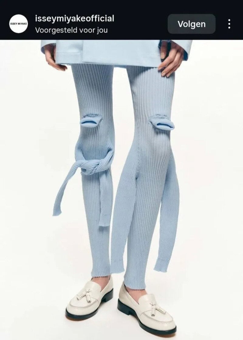 Light blue ripped pants with long straps hanging down, paired with white shoes.