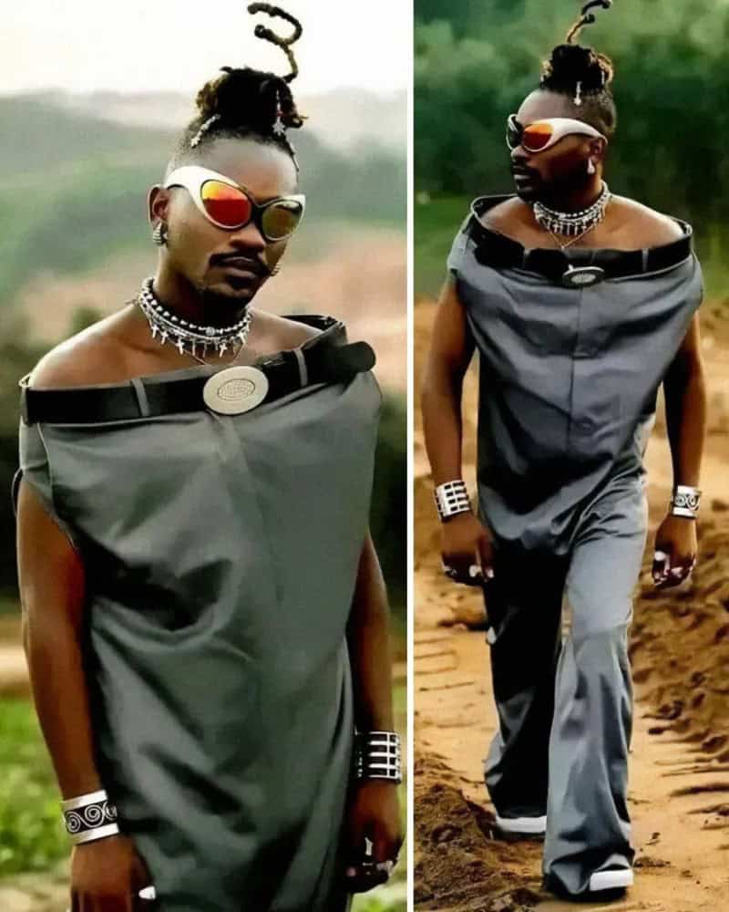 Person in oversized gray dress with sunglasses and jewelry, outdoors.